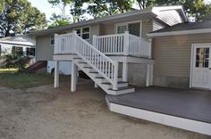 a house with stairs leading up to the front door and side porchs on both sides