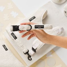 a person holding a pair of white slippers on top of a towel covered table