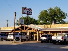 several cars parked in front of a restaurant with a sign that says mary's cafe