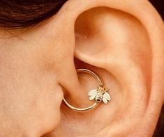 a woman's ear with a small bee on the inside of it and a gold hoop