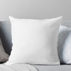 a white pillow sitting on top of a couch next to two gray and white pillows