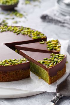 there is a chocolate cake with pistachios on the top and one slice missing