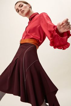 a woman in a red shirt and maroon skirt is dancing with her hands out to the side