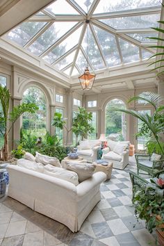 a living room filled with white furniture and lots of plants on top of it's walls