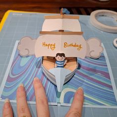 someone is cutting out a birthday card with a paper boat on the front and side