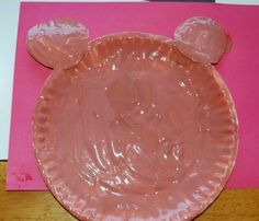 a paper plate shaped like a bear's head with chocolate on it and pink background