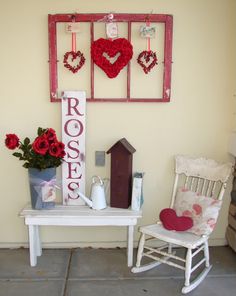 a white rocking chair sitting next to a table with red flowers and hearts on it