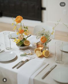 the table is set with yellow and white flowers in glass vases, silverware, and napkins