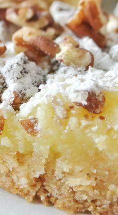 a close up of a piece of cake on a plate with powdered sugar and nuts