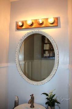 a bathroom with a sink, mirror and lights on the wall above it is shown