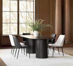 a dining room table with chairs and a potted plant on it in front of a window