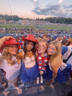 three girls wearing red hats and blue tutus at a football game, posing for the camera