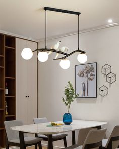 a dining room table with four chairs and a vase on the table in front of it