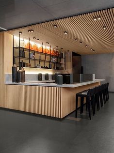 an empty bar with stools and bottles on the counter in front of it,