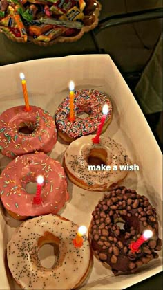 a box filled with lots of donuts covered in sprinkles and lit candles