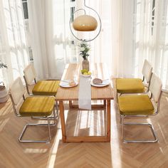 a dining room table with yellow chairs and a potted plant in the center on top