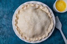 an uncooked pie sitting on top of a white plate next to a fork