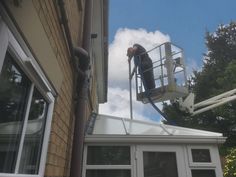 a man on a lift working on the side of a building with windows in front of him