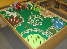 a toy farm with horses, sheep and people in the field on it's play table