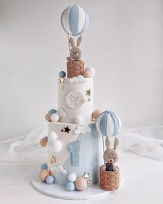 a three tiered cake with balloons and animals on it