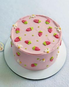 a pink cake decorated with strawberries and daisies