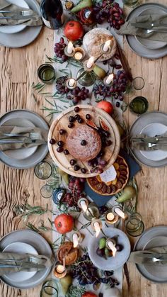 the table is set with plates, silverware and fruit on it for a festive dinner