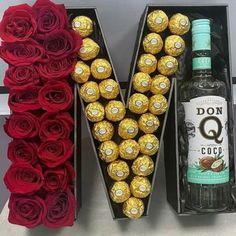 the letter v is made out of chocolates and roses with a bottle of booze