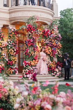 a woman standing in front of a flower covered building