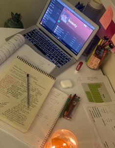 an open laptop computer sitting on top of a desk next to a notepad and pen