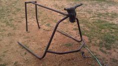 an upside down metal structure in the middle of a field with grass and dirt around it