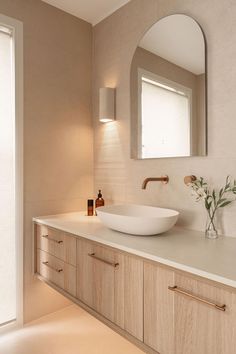 a bathroom sink sitting under a mirror next to a counter top with a vase on it