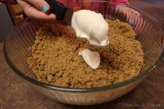 a person is spreading cream on top of some food in a glass bowl with a black plastic spatula