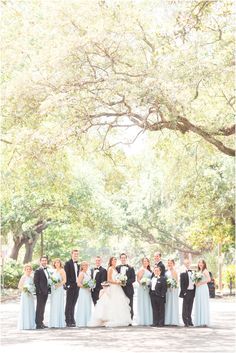 the bridal party is posing for a photo in front of a large oak tree