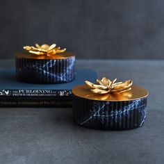 two black and gold decorated boxes sitting on top of each other next to a book