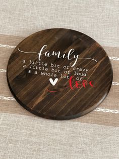 a wooden coaster with the words family on it and a heart in red ink, sitting on a table cloth