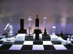 a chess board with white and black pieces on it's sides, in front of a purple wall