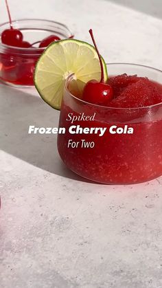 two glasses filled with frozen cherry cola on top of a white counter next to cherries