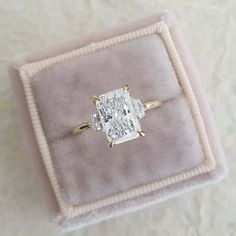 an engagement ring in a velvet box on top of a white carpeted tablecloth