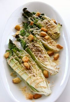 a white plate topped with lettuce covered in parmesan cheese and croutons