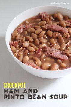 a white bowl filled with ham and pinto bean soup on top of a white table