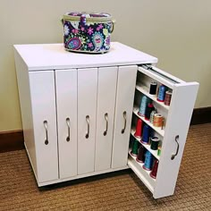 a white cabinet with two doors and some spools of thread