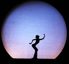 the silhouette of a person standing in front of a large ball with one hand up