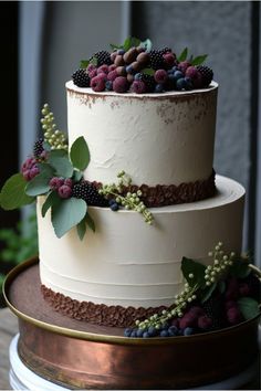 a three tiered cake with berries and leaves on top