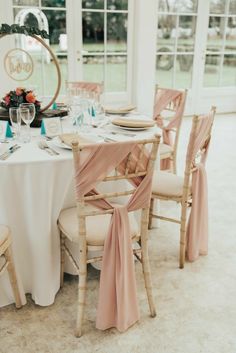 the table is set with white linens and pink sashes for guests to sit at