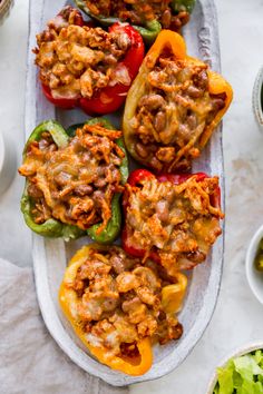 stuffed bell peppers with meat and vegetables on a platter next to bowls of salad