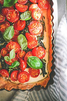 a tomato tart with basil and tomatoes on top