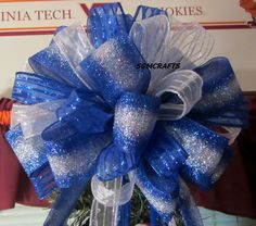 a blue and white bow on top of a christmas tree in front of a sign