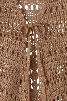 a close up of a knitted shawl with holes in the middle and crochet at the bottom