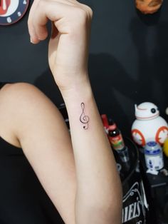 a woman's arm with a musical note tattoo on the left side of her wrist