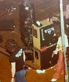 two people standing next to each other in front of a tv set that has been destroyed